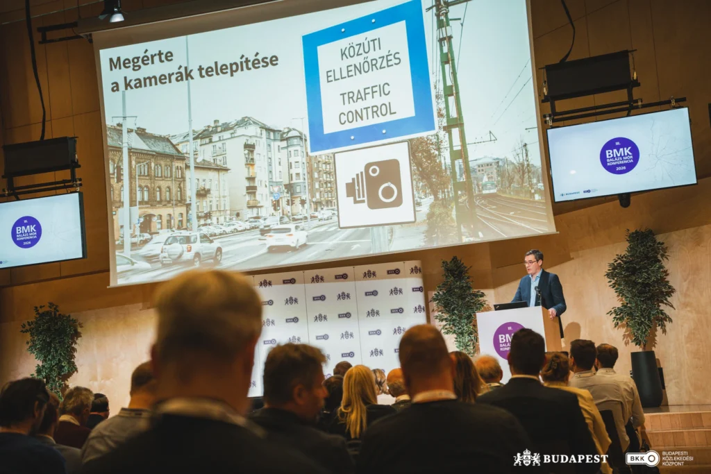 A konferencián a részvevők hallgatják Karácsony Gergely főpolgármester előadását. A kivetitőn szemlétetik, hogy megérte a kamerák telepítése a budapesti utakon.