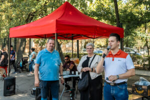 Csernák János mikrofonnal köszönti a szomszédünnep résztvevőit, mellette Cserdiné Németh Angéla polgármester és Makai Ferenc áll a rendezvény helyszínén.