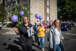A figyelemfelhívó séta résztvevői, az előtérben Katonáné Jordáki Ildikó, mögötte a lila léggömböket vivő csoport.